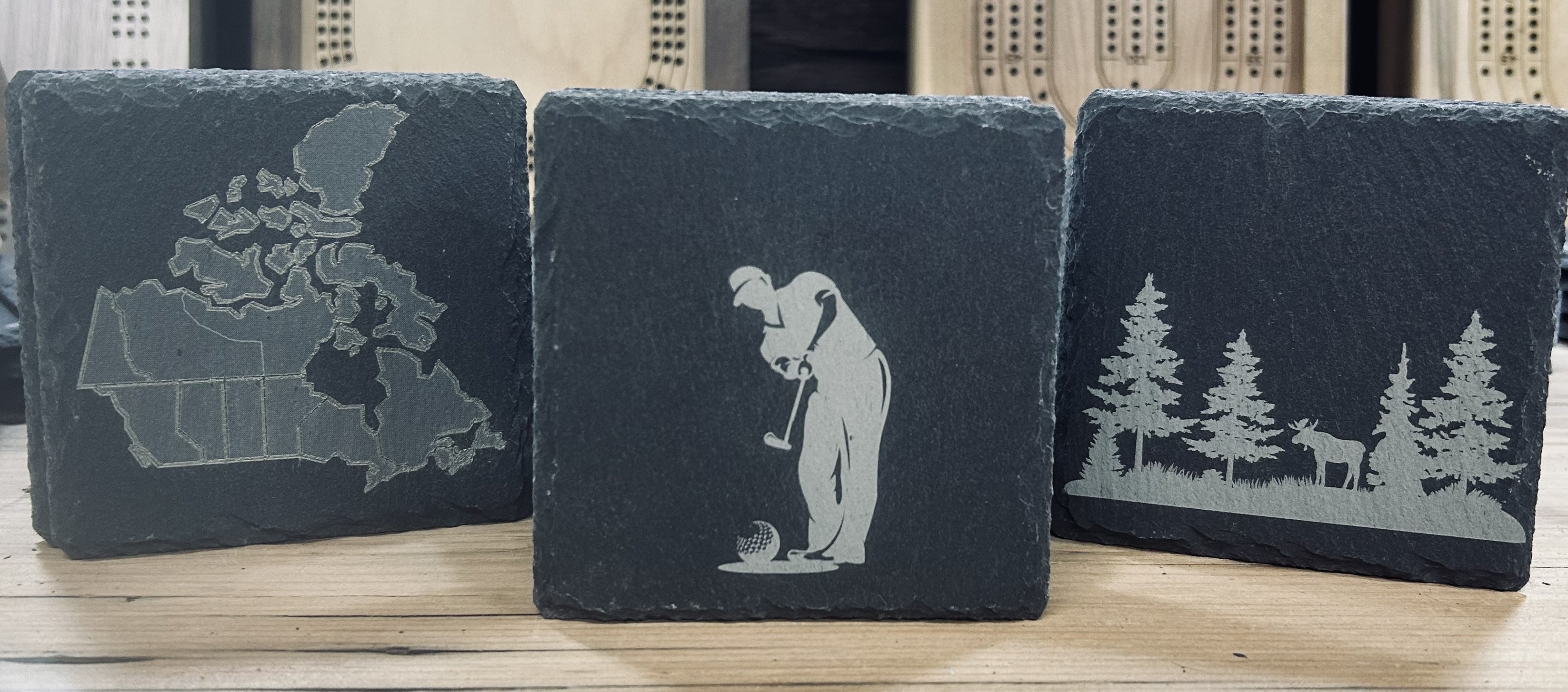 Discontinued product specials featuring slate coasters with Canadian map, golfer, and forest designs.
