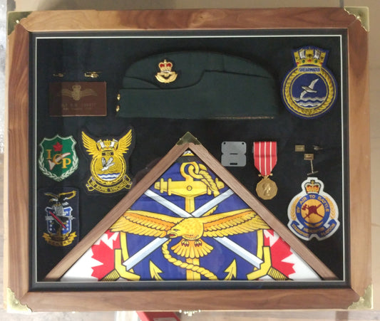 Framed military memorabilia display featuring a cap, medals, and unit badges mounted on a velvet background.